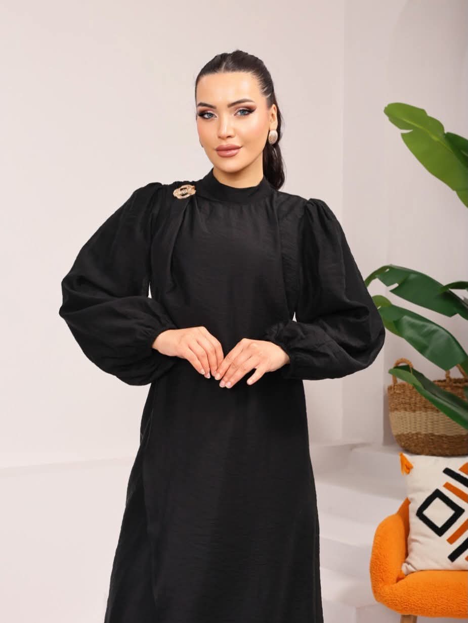Woman wearing a black dress with puffed sleeves in an indoor setting.